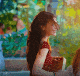 a woman in a red polka dot dress is smiling and holding a book