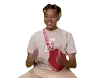 a young man wearing a grey supreme shirt is giving a thumbs up