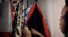 a woman is standing in a closet looking at clothes .