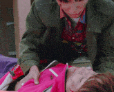 a man in a green jacket is holding a woman in a pink jacket