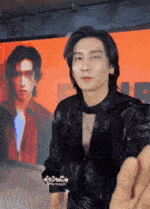 a man in a black jacket is standing in front of a wall with a picture of a man on it