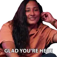 a woman with long hair is smiling with the words glad you 're here below her