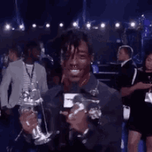 a man is holding a microphone and a trophy in front of a crowd of people .