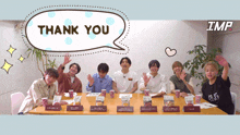 a group of people sitting around a table with a thank you speech bubble