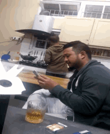 a man is sitting at a table looking at his phone