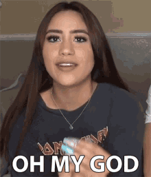 a woman wearing a black shirt with iron maiden on it says " oh my god "