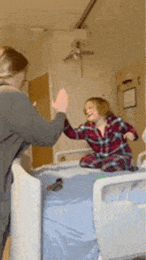a woman and child are giving each other a high five in a hospital room