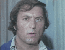 a close up of a man 's face with a white shirt and a blue jacket