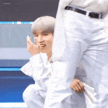 a man in white pants is kneeling down next to another man in white pants and laughing .