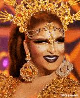 a drag queen wearing a gold crown and earrings