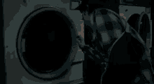 a man is standing in a laundromat looking out the window .