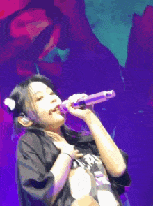 a woman is singing into a microphone with a purple background
