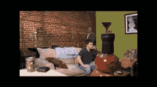 a man sits on a couch in a living room next to a bottle of wine