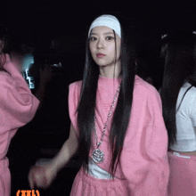 a woman with long hair wearing a headband and a necklace with a circle on it