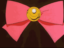 a pink bow with a gold circle in the center