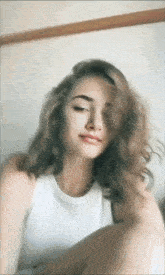 a woman in a white tank top with her eyes closed