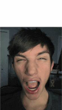 a young man is making a funny face with his mouth wide open
