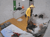 a man in a yellow raincoat stands next to a man in a wheelchair in a bedroom with the number 1 on the wall