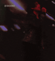 a man in a black jacket is holding a microphone in front of a screen that says @ 2doono on it