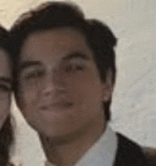 a man in a suit and tie is standing next to a woman in a white shirt .