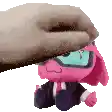 a hand is petting a pink stuffed animal with glasses on .