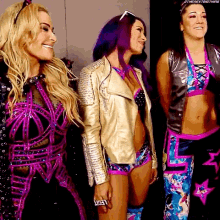 three women are standing next to each other and one has purple hair