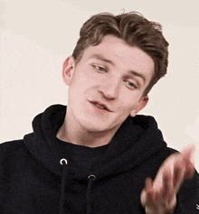 a young man wearing a black hoodie with the letter c on the front