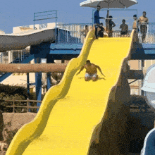 a man is sliding down a yellow water slide