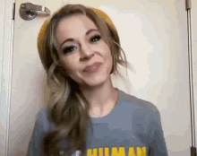 a woman wearing a beanie and a t-shirt is standing in front of a door .