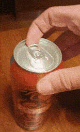 a person is opening a coke can with their fingers