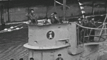 a black and white photo of a group of men standing on a boat