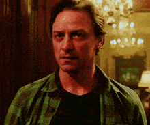 a man wearing a green plaid shirt is looking at the camera