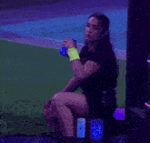 a woman in a black dress is sitting on a stool holding a blue cup .