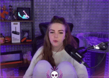 a woman sitting in front of a microphone with a skull on her knee
