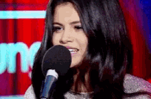 a woman singing into a microphone with a red background