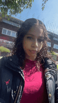 a woman wearing a black jacket and a red shirt
