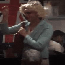 a woman in a wig is dancing in front of a flag