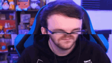 a man wearing glasses and headphones is sitting in a chair .
