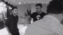 a man wearing a che guevara t-shirt is standing in a room with other men