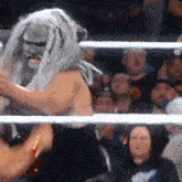 a wrestler wearing a mask and dreadlocks is in a ring