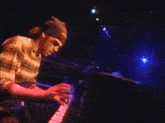 a man in a plaid shirt is playing a piano