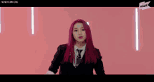a woman with purple hair is wearing a suit and tie and making a funny face .