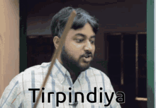 a man in a plaid shirt is holding a stick in his mouth and the word tinpinda is on the bottom
