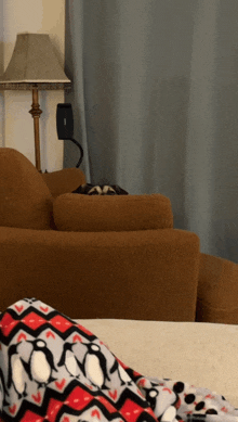 a blanket with penguins on it sits on a couch next to a lamp