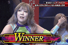 a female wrestler stands in front of a winner banner