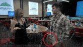 a man in a plaid shirt is talking to a woman in front of a sign that says elbbrus