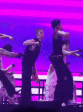 a man in a black tank top is dancing on a stage with a purple background