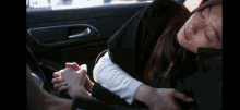 a woman is sleeping in a car while a man holds her hand