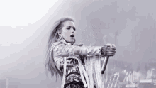 a woman in a white jacket is singing into a microphone on stage .