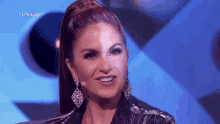 a woman with a ponytail is smiling in front of a microphone on a stage .